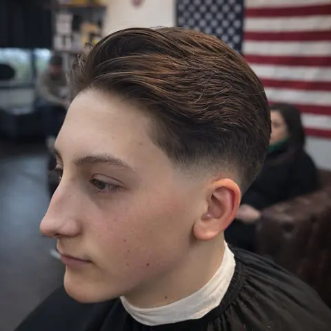 Low fade with a long top swept back, seen from the side
