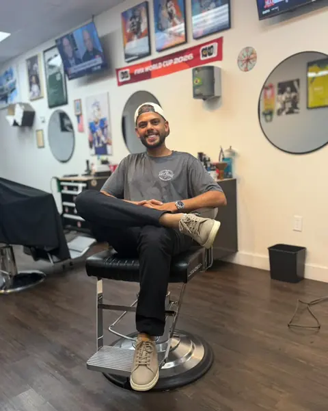 Brenner, co-owner and barber, sitting in a barber chair at Art Zone