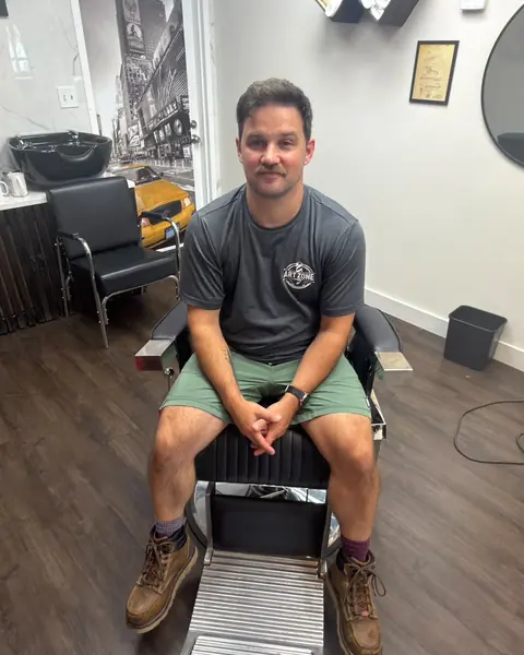 Tim, barber at Art Zone, sitting in a barber chair